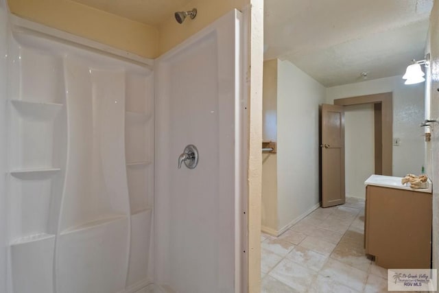 full bathroom featuring a stall shower, vanity, and baseboards