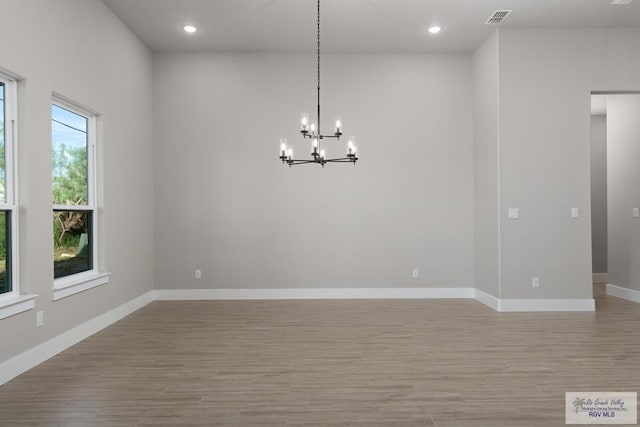 unfurnished room with light wood-type flooring and a chandelier