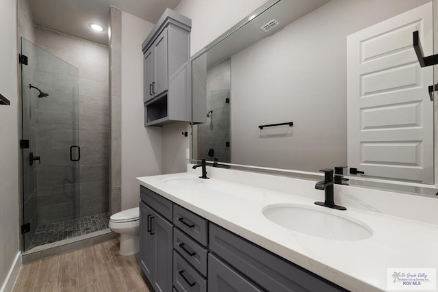 bathroom with walk in shower, vanity, wood-type flooring, and toilet