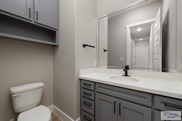 bathroom with hardwood / wood-style floors, vanity, and toilet