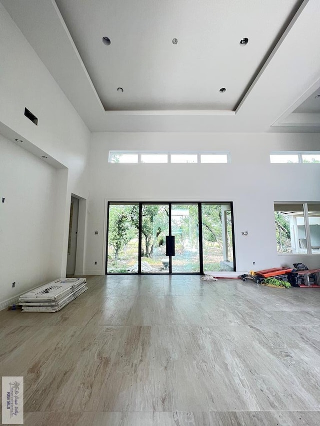 unfurnished living room with hardwood / wood-style flooring, a towering ceiling, and a tray ceiling