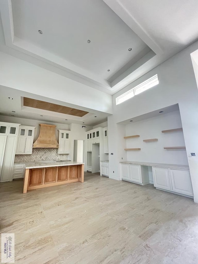 unfurnished living room featuring a high ceiling and a raised ceiling