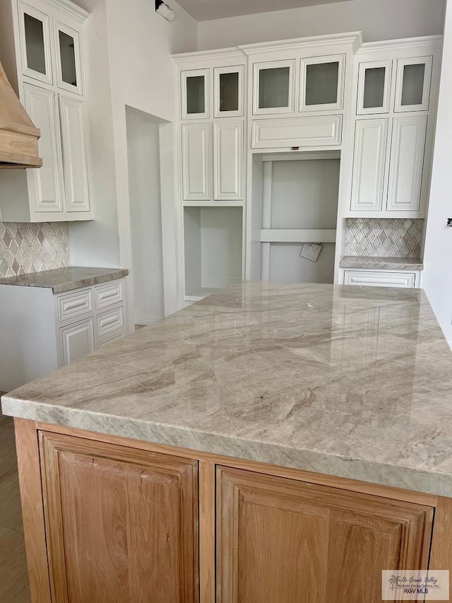 kitchen featuring ventilation hood, tasteful backsplash, and white cabinetry