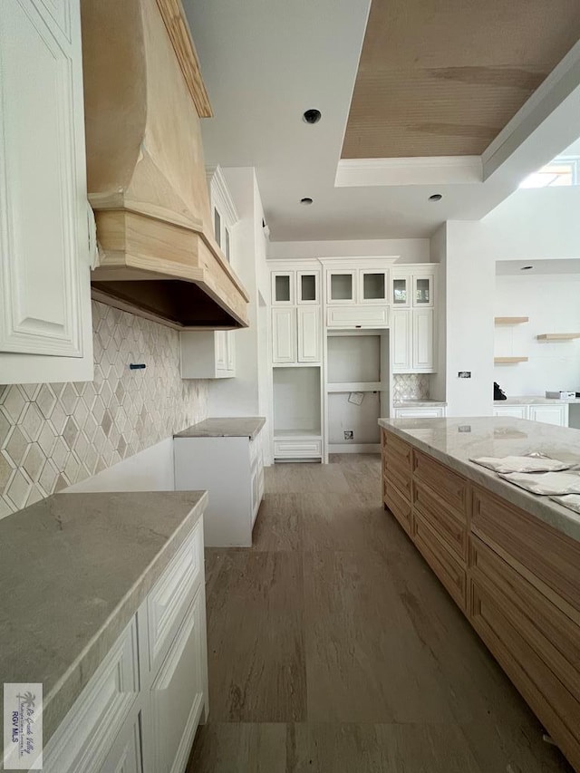 kitchen featuring tasteful backsplash, hardwood / wood-style flooring, white cabinets, and custom exhaust hood