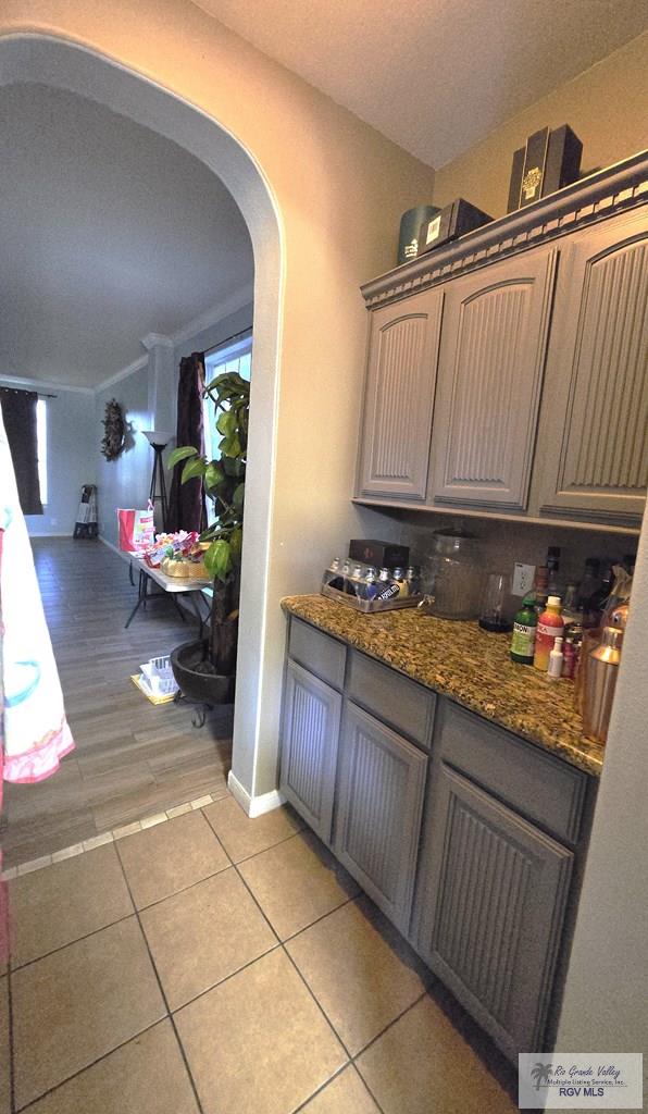 bar with dark stone counters and light hardwood / wood-style flooring