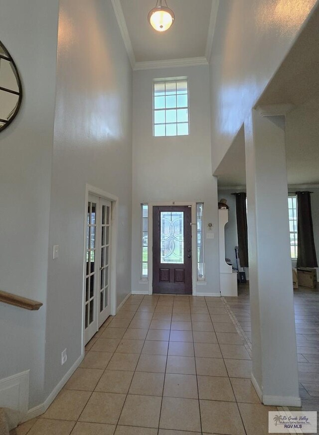 tiled entrance foyer featuring crown molding, french doors, and a towering ceiling