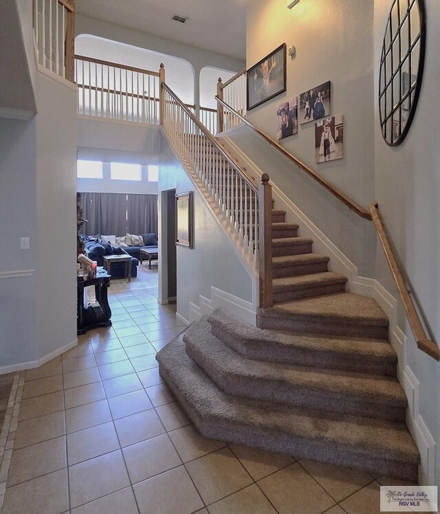 staircase with tile patterned flooring and a high ceiling