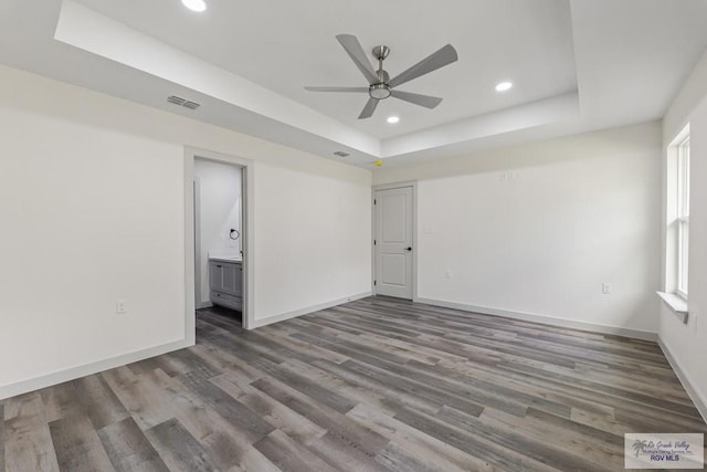 spare room featuring a tray ceiling, a wealth of natural light, and hardwood / wood-style floors