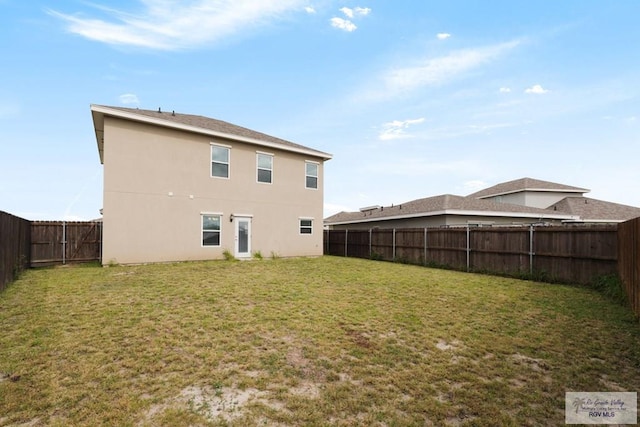 rear view of property with a lawn, a fenced backyard, and stucco siding