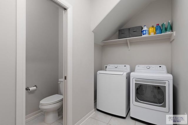 clothes washing area with laundry area, washer and clothes dryer, baseboards, and light tile patterned floors