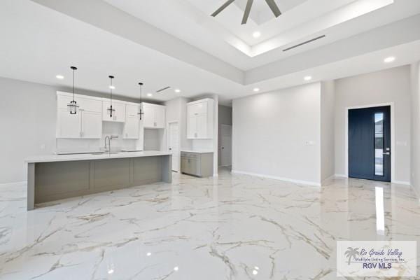 kitchen featuring recessed lighting, a raised ceiling, white cabinets, and marble finish floor