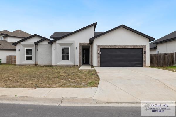 view of front of house featuring concrete driveway, stucco siding, an attached garage, fence, and a front yard