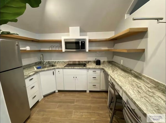 kitchen with light stone counters, stainless steel appliances, sink, and white cabinets