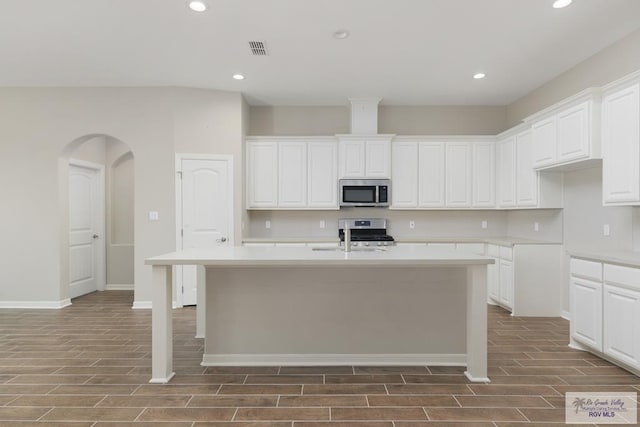 kitchen featuring white cabinets, hardwood / wood-style flooring, an island with sink, and appliances with stainless steel finishes