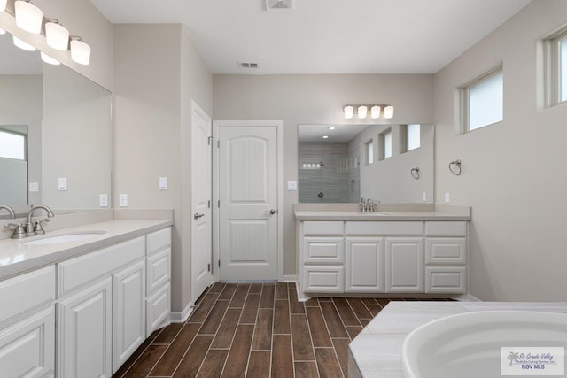 bathroom featuring tiled shower, wood-type flooring, and vanity