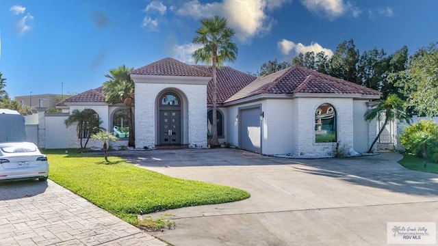 mediterranean / spanish home featuring a garage and a front yard