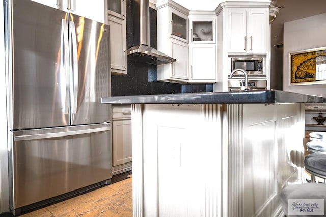 kitchen featuring wall chimney exhaust hood, stainless steel appliances, decorative backsplash, and white cabinets