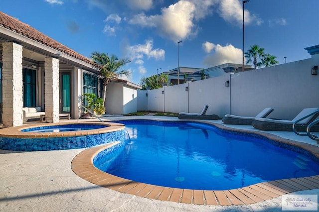 view of swimming pool with an in ground hot tub