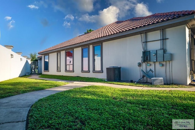 rear view of property featuring cooling unit and a yard