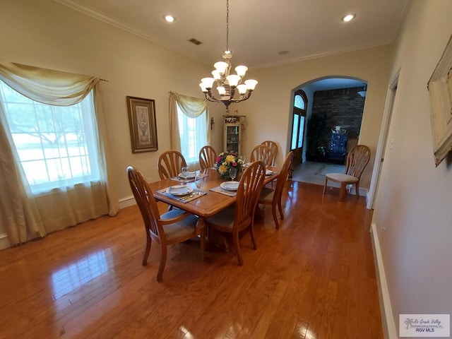 dining area featuring a chandelier, wood-type flooring, and ornamental molding