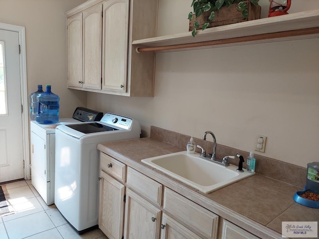 laundry area featuring cabinets, light tile patterned floors, washer and clothes dryer, and sink