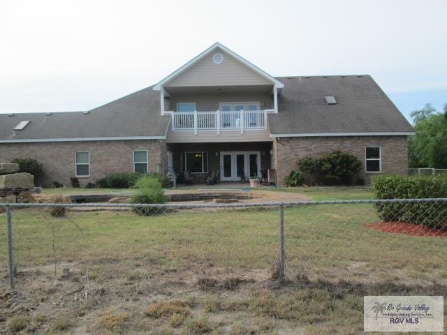 back of house featuring a balcony and a yard