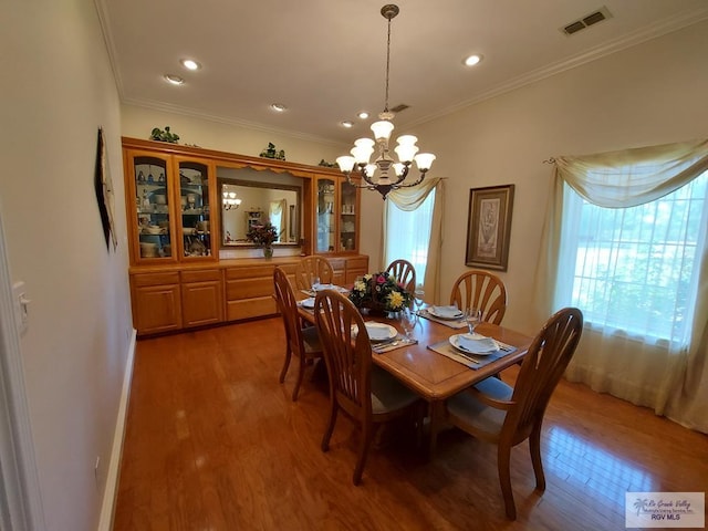 dining area featuring wood-type flooring, ornamental molding, and a chandelier