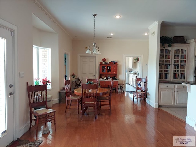 dining room with hardwood / wood-style floors, an inviting chandelier, and ornamental molding