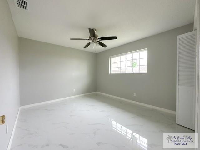 unfurnished bedroom featuring marble finish floor, a ceiling fan, visible vents, and baseboards