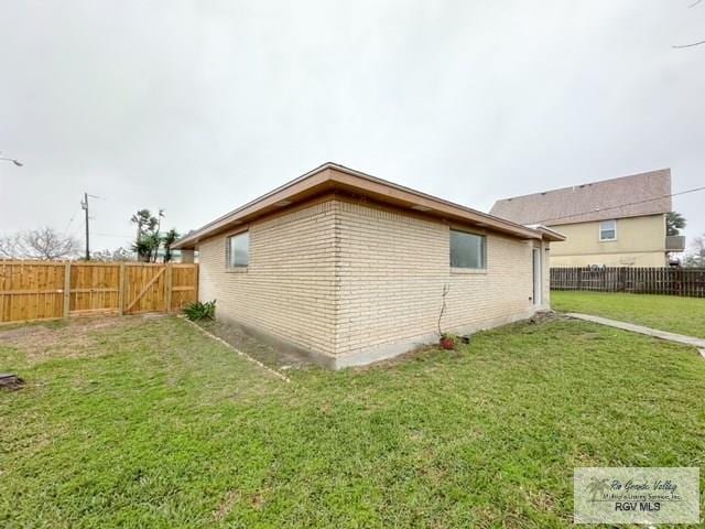 view of property exterior featuring brick siding, a lawn, and a fenced backyard