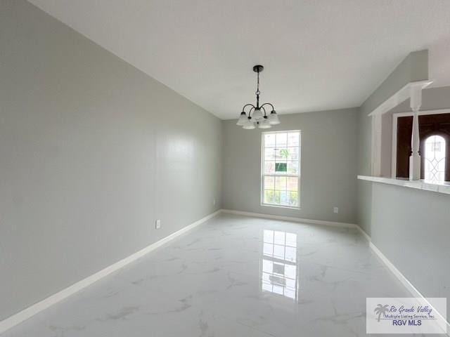 unfurnished dining area featuring a chandelier, marble finish floor, and baseboards