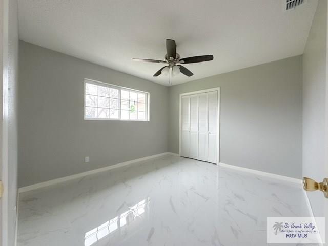 unfurnished bedroom with a closet, marble finish floor, visible vents, and baseboards