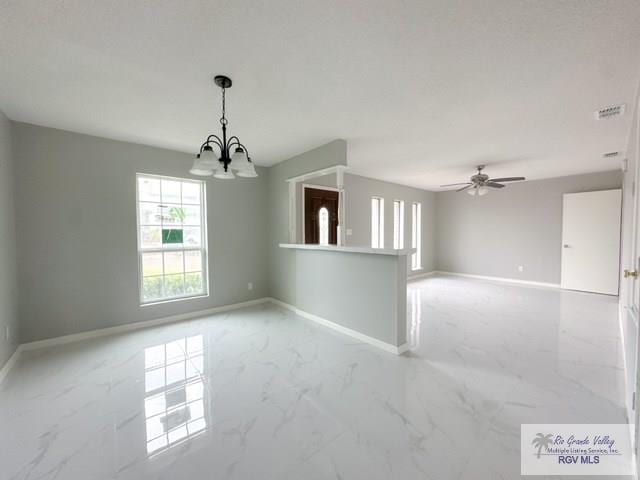 empty room with marble finish floor, visible vents, baseboards, and ceiling fan with notable chandelier