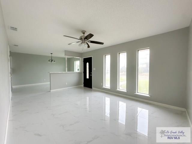 spare room with ceiling fan with notable chandelier, marble finish floor, visible vents, and baseboards