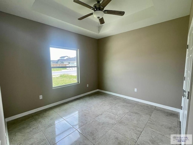 spare room with light tile patterned floors, a raised ceiling, and ceiling fan