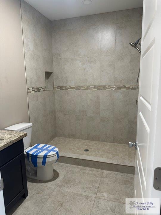 bathroom featuring tiled shower, vanity, and toilet