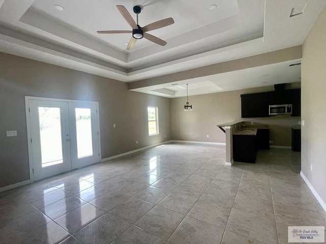 unfurnished room featuring french doors, ceiling fan with notable chandelier, and a tray ceiling