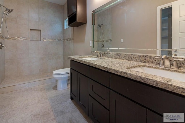 bathroom featuring tiled shower, vanity, toilet, and tile patterned flooring