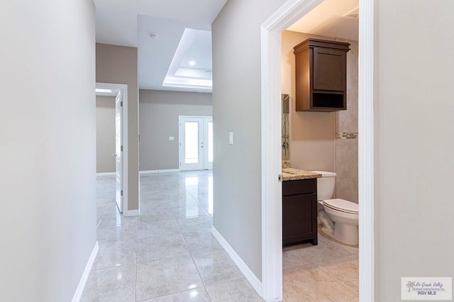 hallway featuring light tile patterned floors and a raised ceiling