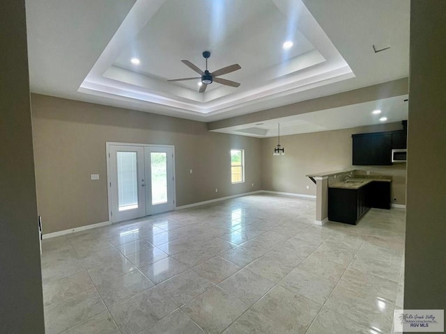 spare room with a raised ceiling, ceiling fan, and french doors