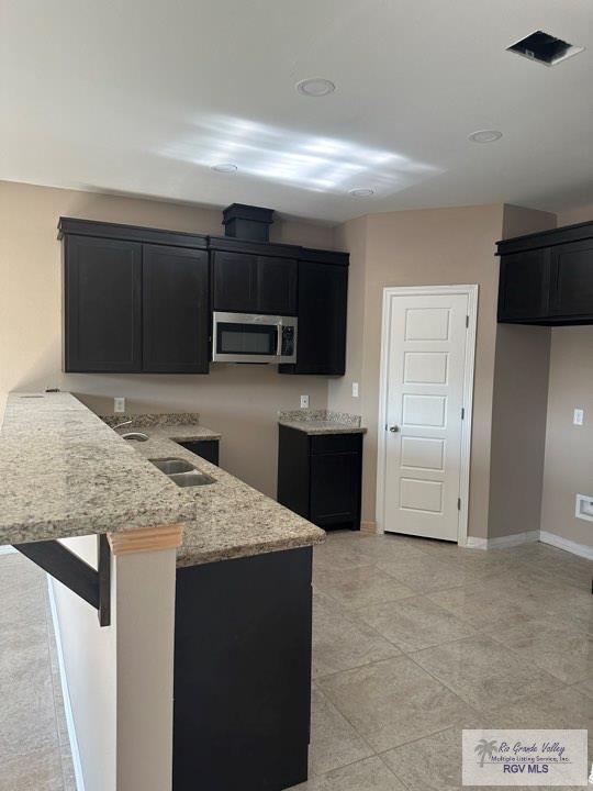 kitchen featuring kitchen peninsula and light stone counters