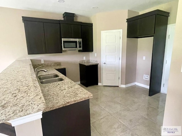 kitchen featuring light tile patterned flooring, light stone countertops, and sink