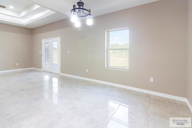 empty room featuring french doors, light tile patterned floors, a healthy amount of sunlight, and a notable chandelier