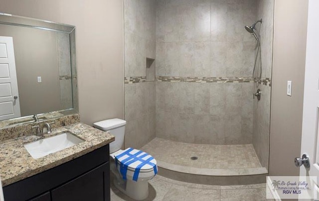 bathroom featuring a tile shower, vanity, toilet, and tile patterned floors