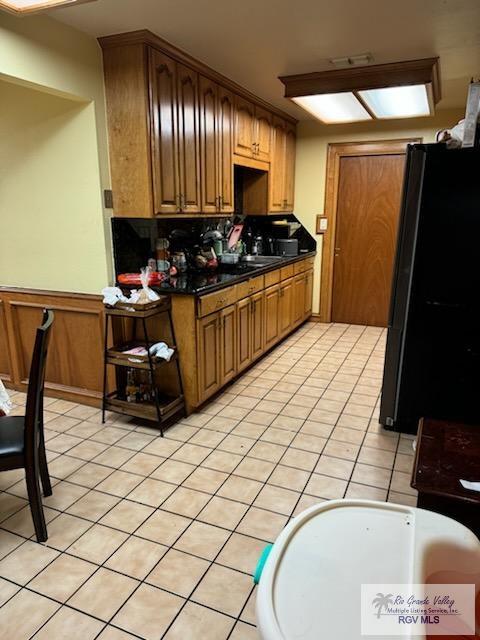 624 Waterside Dr, Brownsville, TX 78521 - kitchen with black refrigerator, decorative backsplash, and light tile patterned floors