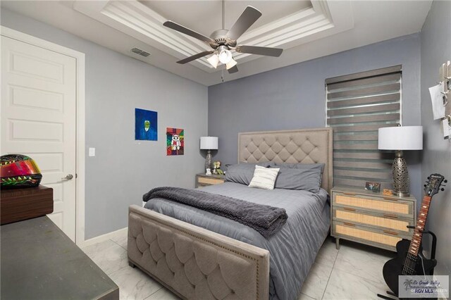 bedroom with light marble finish floors, a raised ceiling, and ceiling fan