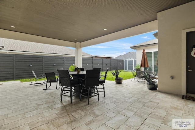 view of patio with outdoor dining area, a storage unit, and an outdoor structure