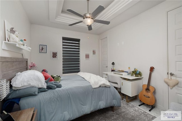 bedroom with a ceiling fan and a tray ceiling