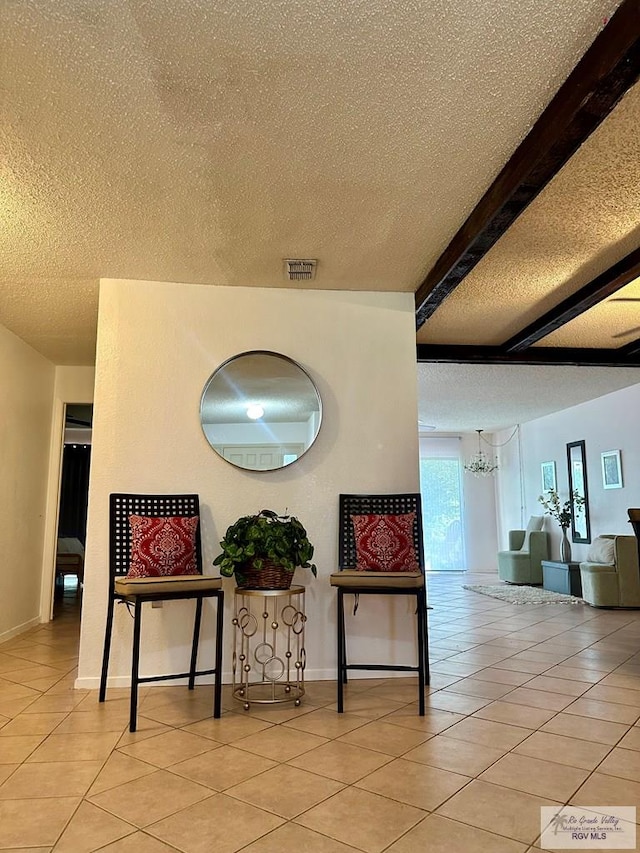 interior space featuring beam ceiling, a textured ceiling, an inviting chandelier, and light tile patterned flooring