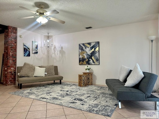 living room featuring ceiling fan with notable chandelier, a textured ceiling, and light tile patterned flooring